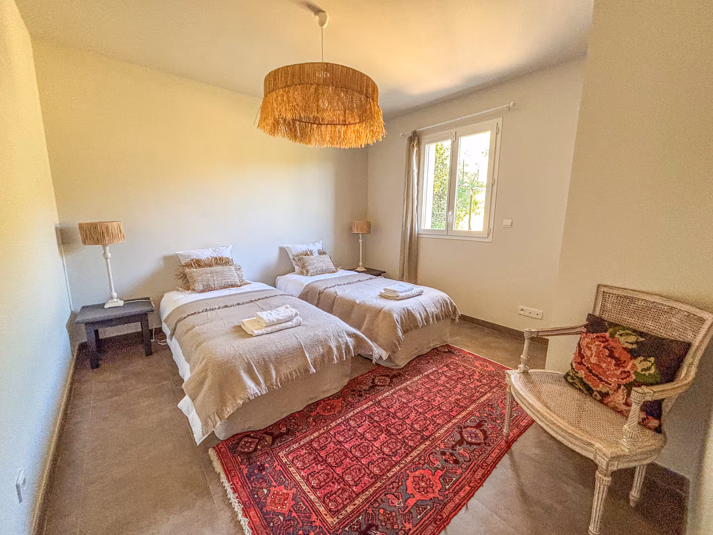 Chambre à deux lits jumeaux, tapis ancien et lumière du matin