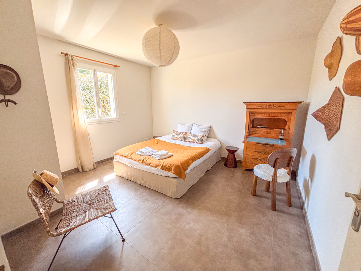 Chambre aux tons ocre, lit double et fenêtre sur le jardin