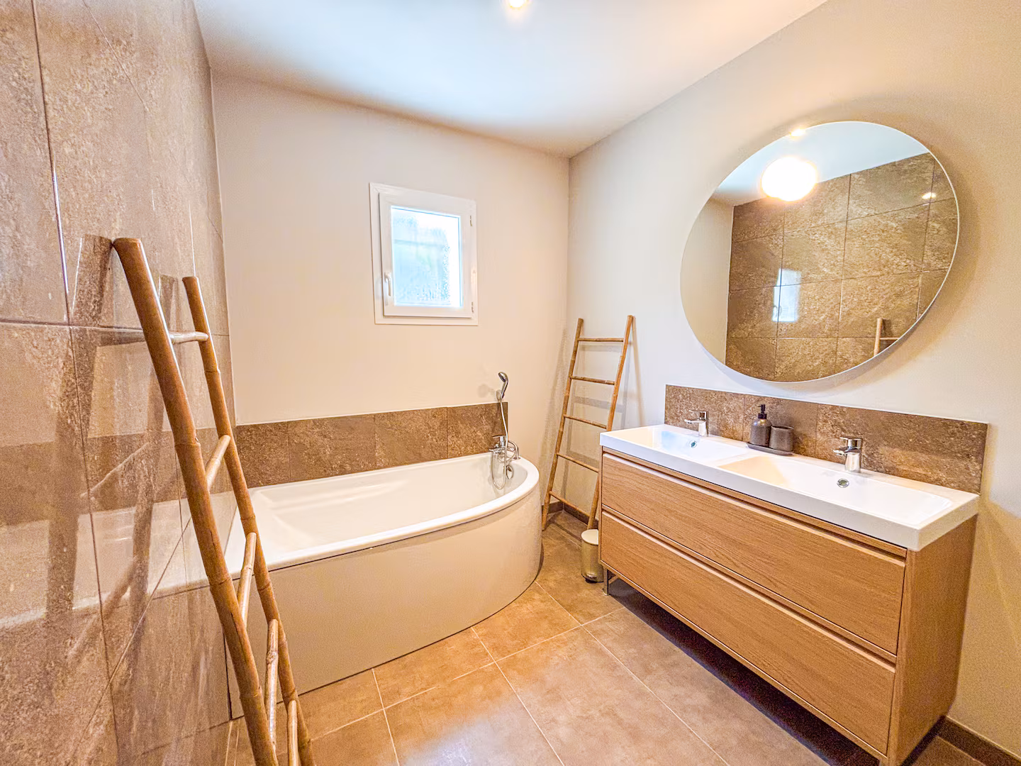 Salle de bain en pierre claire, baignoire d'angle et double vasque