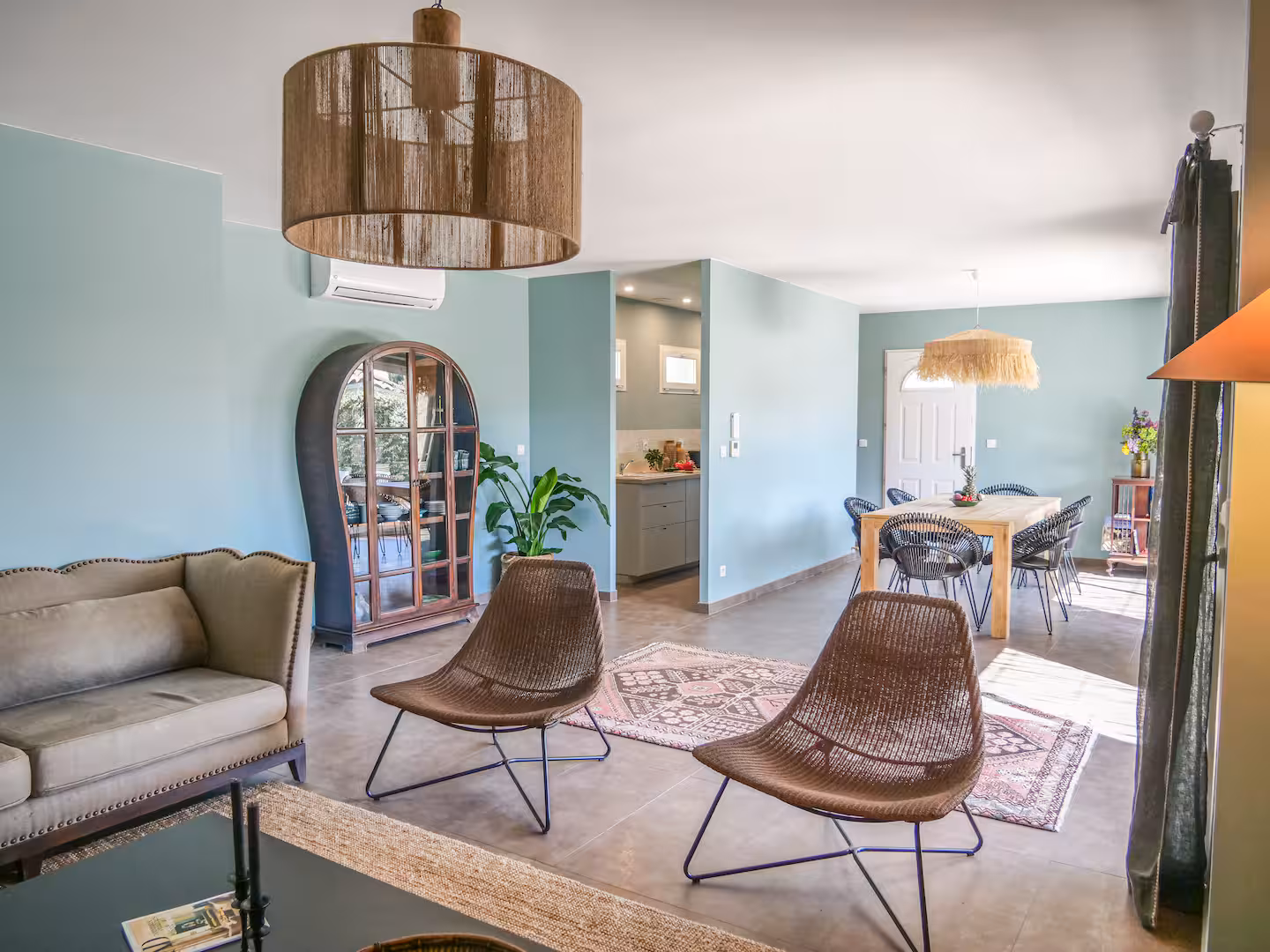 Séjour aux murs vert d'eau, fauteuils en cuir et suspension en fibre